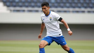 A photo of a Puebla player in action, with a determined look on their face, wearing their home kit, which is a white...