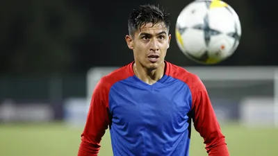 A frustrated 30-year-old Puebla defender, build athletic, in a plain blue and red training top, sweat-drenched fabric...