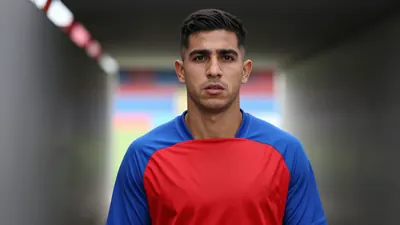 Mid-30s Puebla midfielder, athletic build, intense gaze, head-and-shoulders, wearing a plain blue and red training top...
