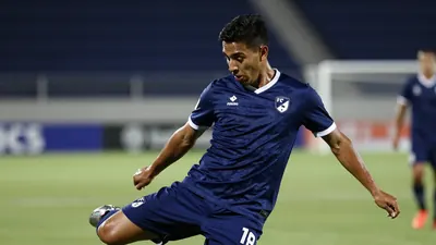 A Puebla FC player in a dark blue jersey with white trim, mid-kick during a match