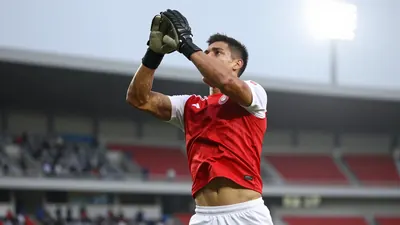 A tight action crop of a Puebla player in a floodlit stadium, wearing a red jersey with white sleeves, and white shorts...