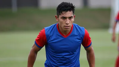 Mid-shot of a muscular 24-year-old Puebla midfielder, shoulders forward, intense eyes fixed on an unseen opponent...