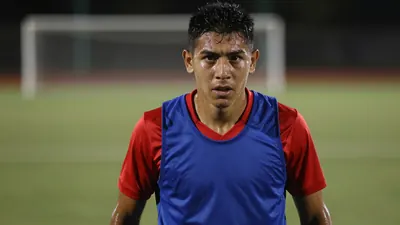 A determined, athletic 28-year-old Puebla midfielder, wearing a plain blue and red training top, intense eyes locked...