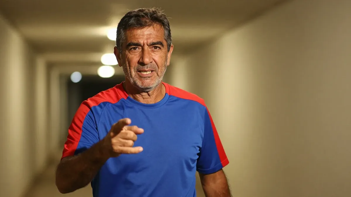 A 50-year-old, 5'10" male coach with a rugged build, wearing a plain blue and red Puebla training top made of lightweight...