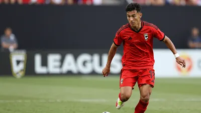 A young Puebla player in a red jersey, midfield build, age 25-30, wearing a determined expression as he sprints with the...