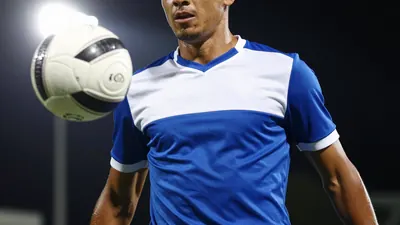 A photorealistic image of a Puebla player in action, showing the player's face and the ball in mid-air, with the player's...